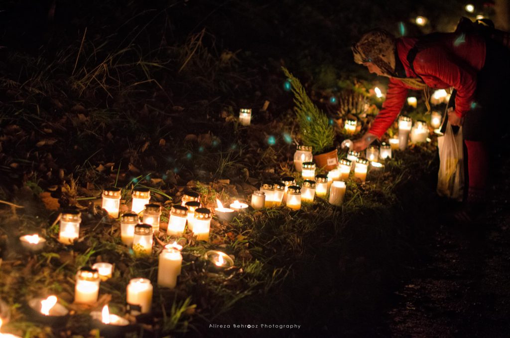 Woman lighting candles on All Saints’ Day.Skogskyrkogården cemetry, Stockholm.